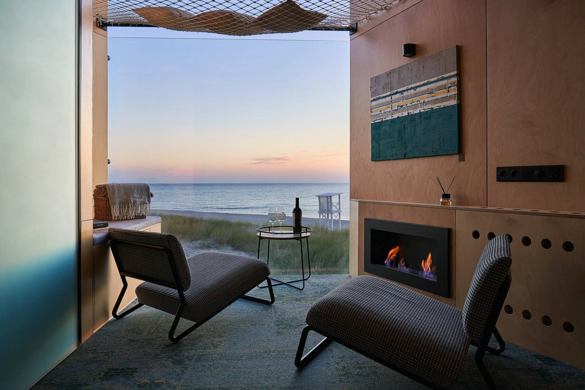 Камин, два кресла, бутылка вина и Балтийское море за панорамным окном.