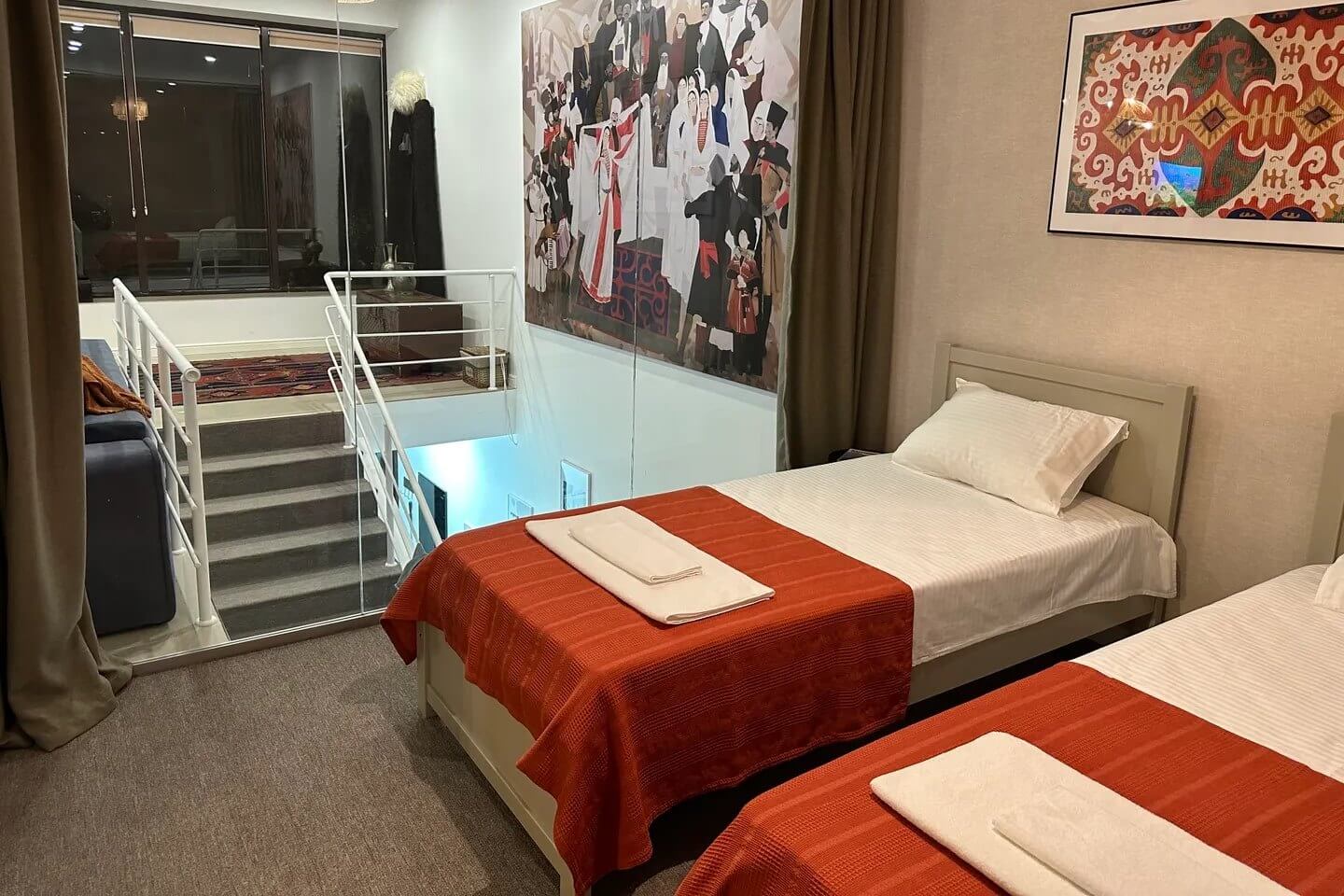 Зона спальни расположена на втором уровне. Кровати накрыты оранжевым саше.