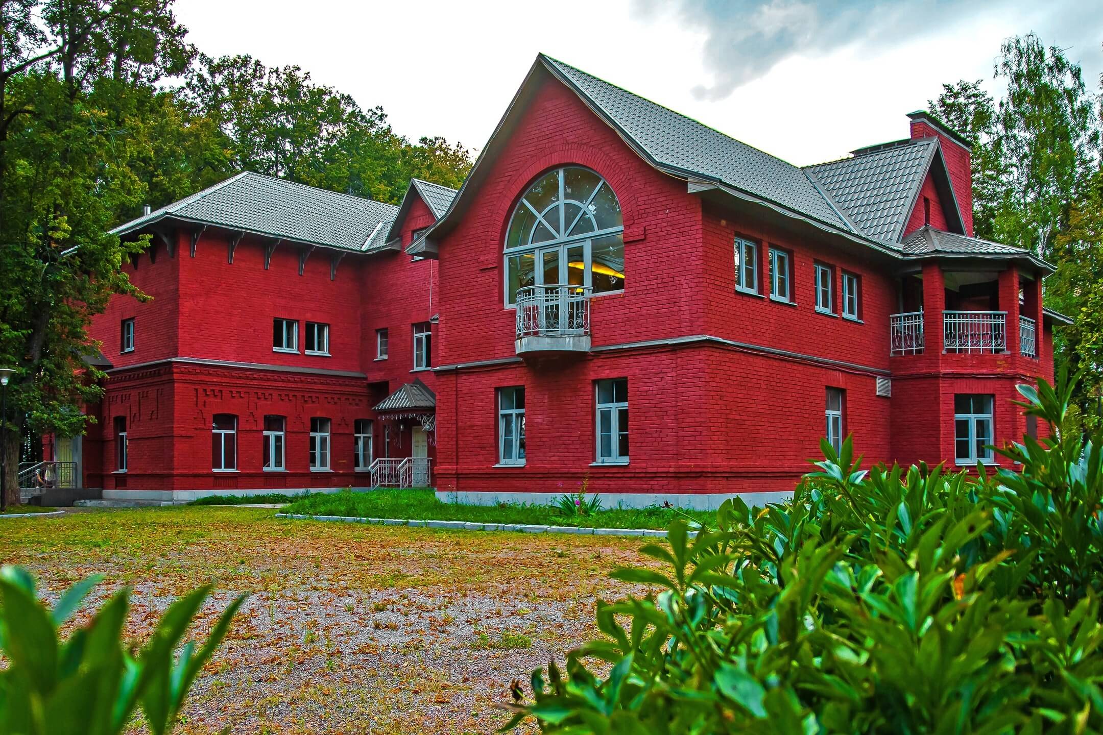 Фасад гостевого коттеджа выкрашен в насыщенный малиновый цвет.