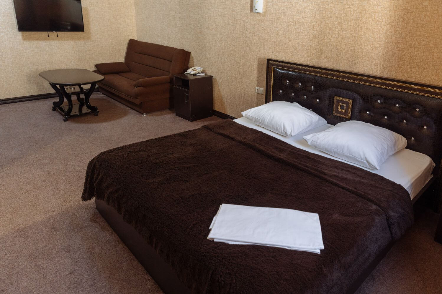 Кровать накрыта коричневым, теплым покрывалом.