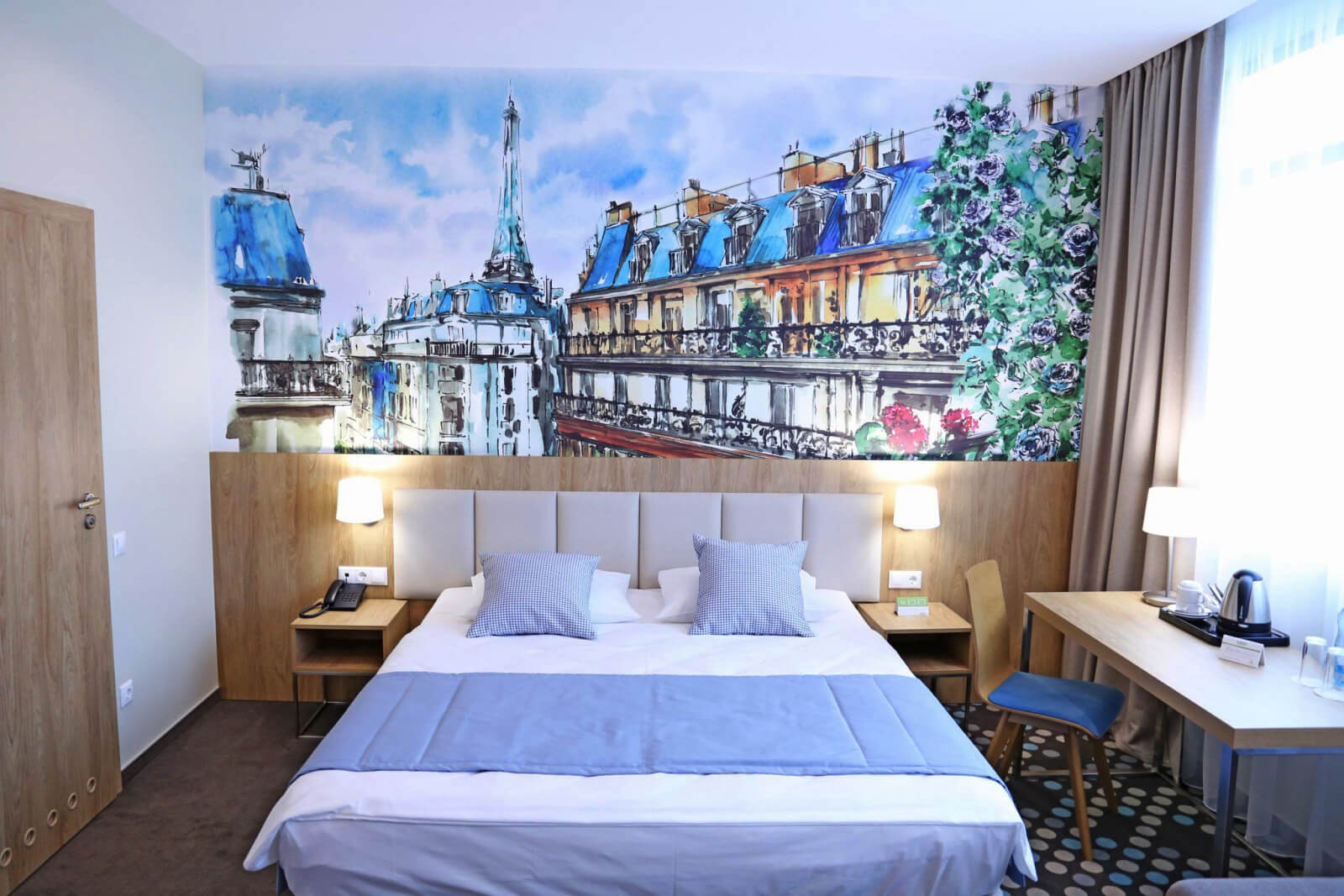 На стене у изголовья кровати красивое изображение парижского городского пейзажа.