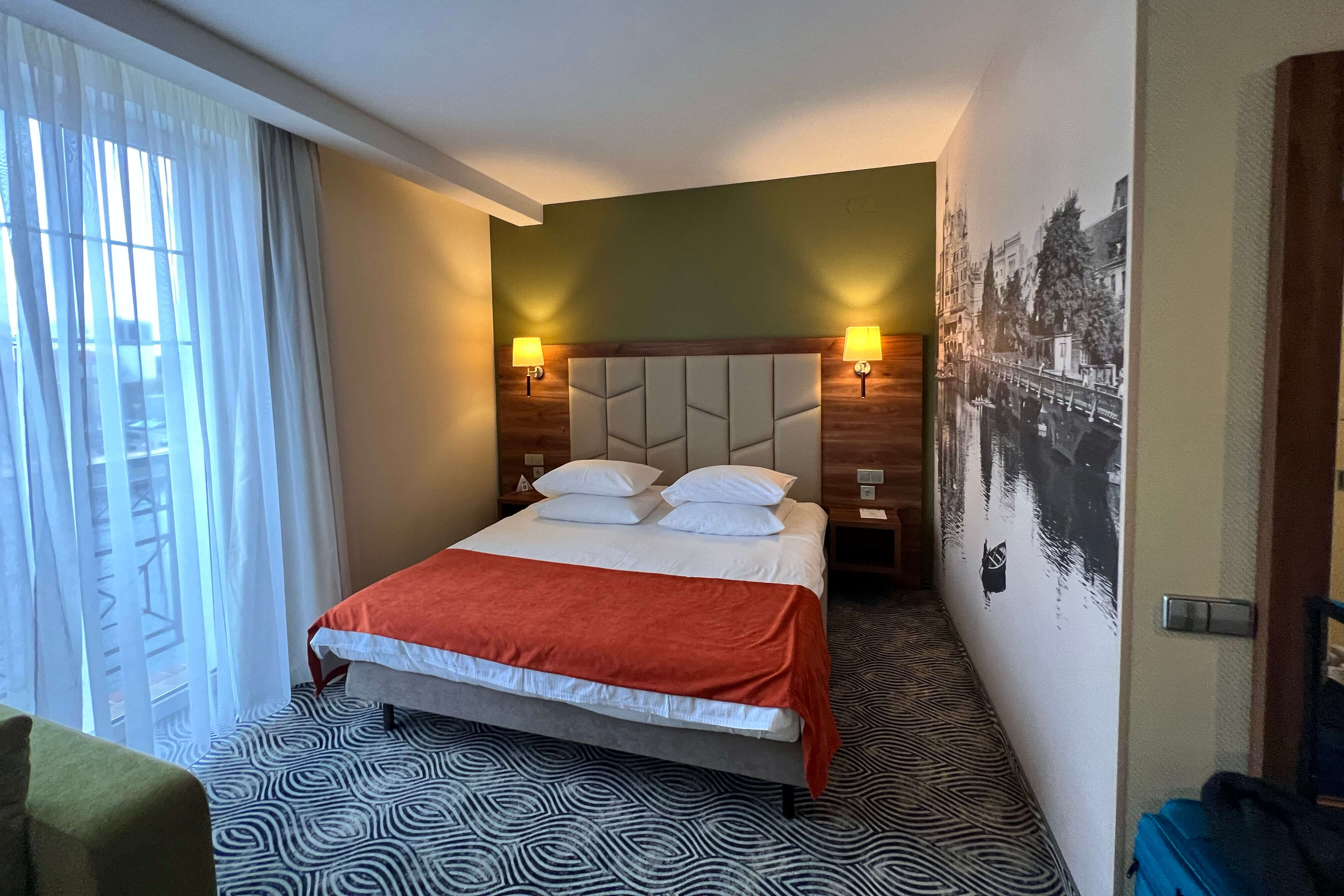 Отель «Kaiserhof» 4*. На стенах - фотообои старого Калининграда, кровать накрыта коричнево-бордовым саше.